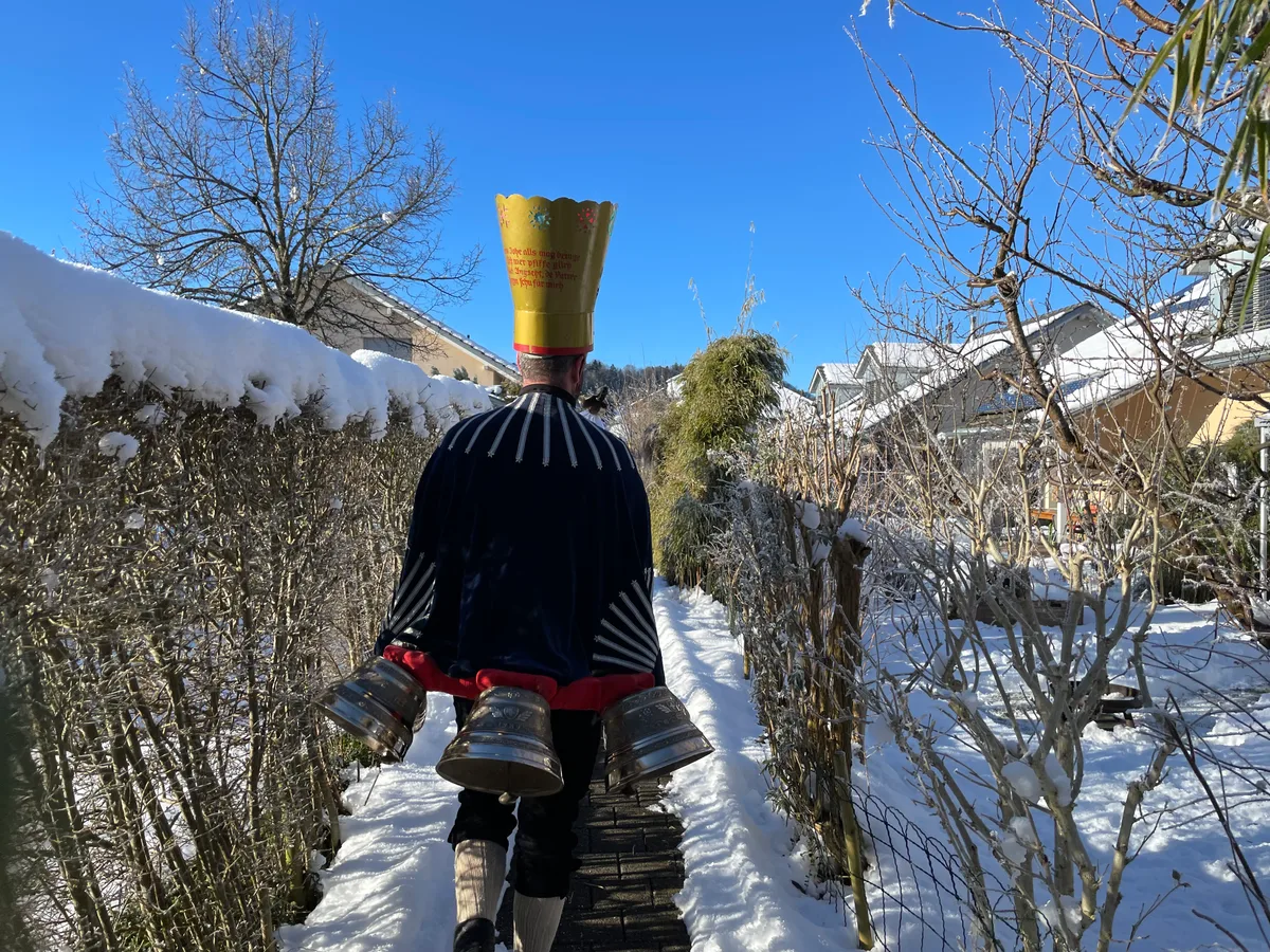 Ein Silvesterchlaus läuft durch einen Garten.